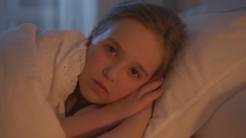 anxious child lying in bed awake